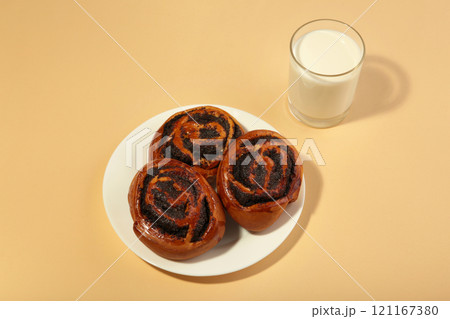 Bun with poppy seeds and glass of milk on beige wooden background. 121167380
