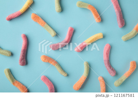 Top view of colorful gummy jelly worm candies on blue background. 121167581