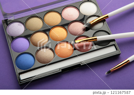 Professional makeup palette with brushes on purple background. 121167587