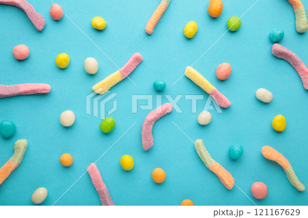Gummy worm candies and pills on blue background. 121167629