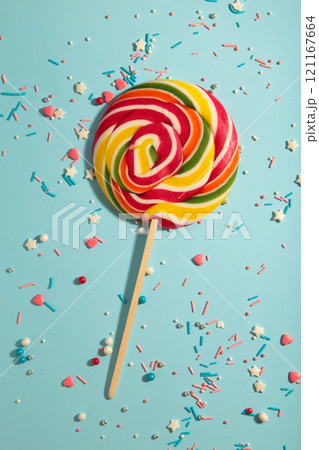 Colorful spiral lollipop with sprinkling on blue background. Vertical photo Colorful spiral lollipop with sprinkling on blue background. Vertical photo 121167664