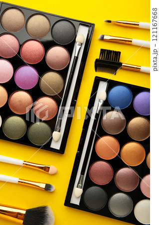 Professional makeup palette with brushes on yellow background. Vertical photo. 121167668