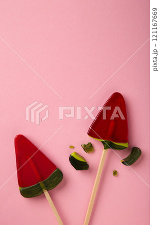 Red lollipop candy broken in pieces on pink background Red lollipop candy broken in pieces on pink background 121167669