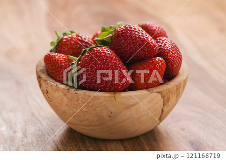 Ripe strawberries in wooden bowl on wood background 121168719