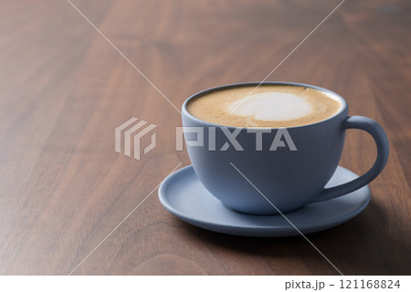 Fresh cappuccino in a blue cup on walnut table with copy space 121168824