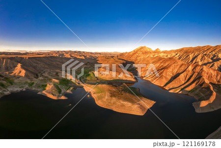 Panoramic aerial view on picturesque Azat reservoir and Eranos mountain at bright sunny evning sunset. Lake with blue water in arid area and Yeranos mountains range. Beautiful landscape. Armenia. Panoramic aerial view on picturesque Azat reservoir and Eranos mountain at bright sunny evning sunset. Lake with blue water in arid area and Yeranos mountains range. Beautiful landscape. Armenia. 121169178