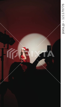 Sexy happy woman with long hair in New Year's hat and red dress posing on white background at New Year's party style photo shoot 121170776