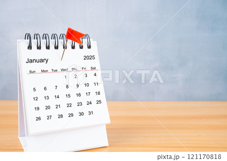 January 2025 calendar and red push pin on table. January 2025 calendar and red push pin on table. 121170818