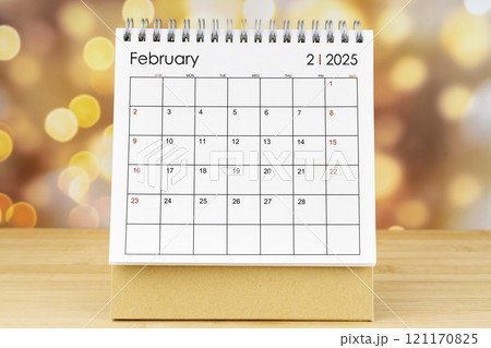 February 2025 desk calendar on wooden table with gold light bokeh. February 2025 desk calendar on wooden table with gold light bokeh. 121170825