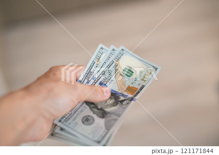 A hand passes hundred dollar bills to another person A hand passes hundred dollar bills to another person 121171844