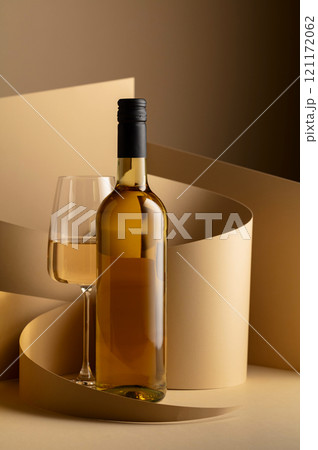 Bottle and glass of white wine on a beige background. Bottle and glass of white wine on a beige background. 121172062