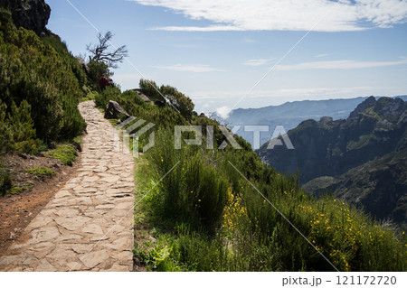 Tourists walking stony hiking trail on the edge of the mountain, Madeira, Portugal 121172720