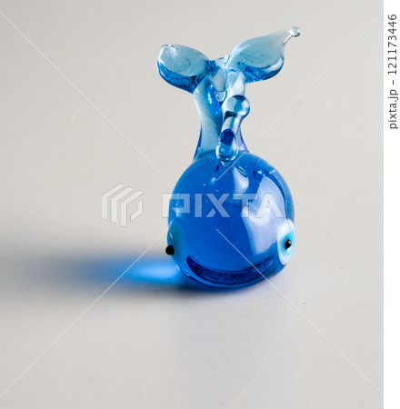 A figurine of a blue whale, specially made of glass on a white background. 121173446