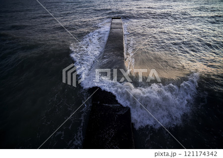 Landscape with a stone pier and raging waves in the sea. Landscape with a stone pier and raging waves in the sea. 121174342