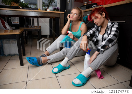 Two friends savor a delightful break from their cleaning tasks, dressed in cozy, relaxed attire Two friends savor a delightful break from their cleaning tasks, dressed in cozy, relaxed attire 121174778