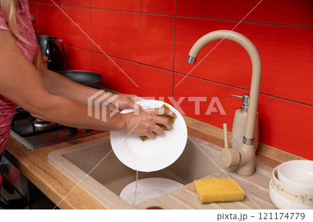 A person washes dishes in a colorful kitchen, emphasizing cleanliness and personal responsibility A person washes dishes in a colorful kitchen, emphasizing cleanliness and personal responsibility 121174779