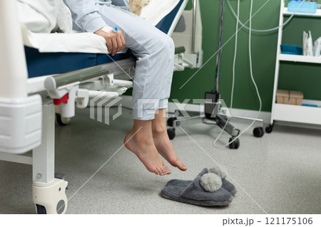 A patient is peacefully resting in their hospital room while wearing comfortable slippers 121175106