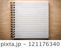 A classic spiral notebook is currently resting on a wooden table 121176340