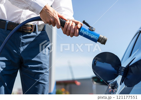 Man holds a hydrogen fueling nozzle on a hydrogen filling station. Refueling car with hydrogen fuel 121177551
