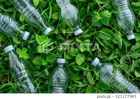 Three plastic bottles with a green recycling symbol on a wooden surface 121177965