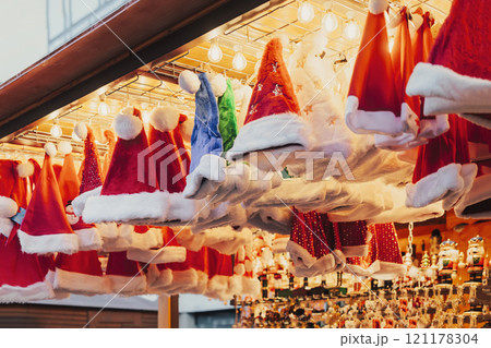 Bright display of red and white Santa hats with festive lighting at Christmas market stall 121178304