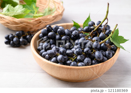 Black grapes in wooden bowl on white table, Seedless grapes 121180369