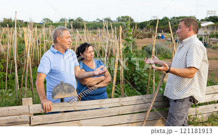Quarrel of neighbors in country in village. Elderly couple and neighbor are in conflict near wooden fence 121181913