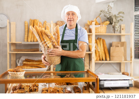 Elderly man with basket of baguettes in bakery 121181937