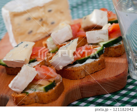 Canape from soft cheese, cucumber and salmon at bread, served on desk 121182042