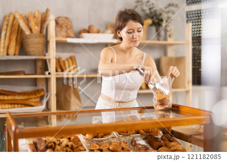 European young woman visitor puts croissant in plastic disposable bag 121182085