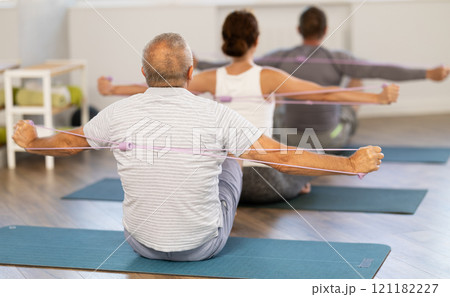Group of elderly women and men doing stretching exercises with resistance band. Good mood and healthy lifestyle concept 121182227