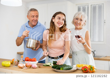 Portrait of mature man, woman and daughter preparing family dinner at kitchen table 121182282