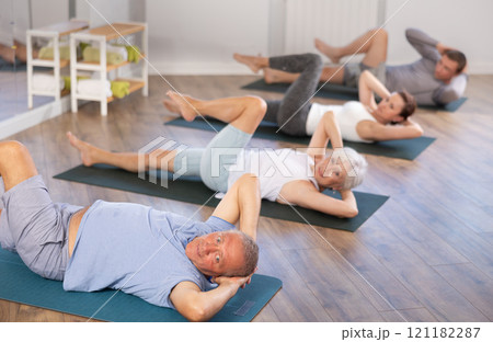 Elderly man performs exercises to strengthen abdominal muscles during group workout 121182287