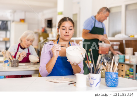 woman paints vase that she made herself 121182314