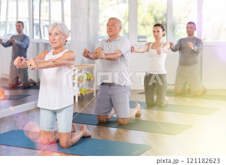 Mature woman bring together and spread your straightened arms at chest level with resistance band Mature woman bring together and spread your straightened arms at chest level with resistance band 121182623