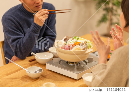 冬の夜のリビングで夕食の鍋料理を楽しむミドル夫婦 121184021