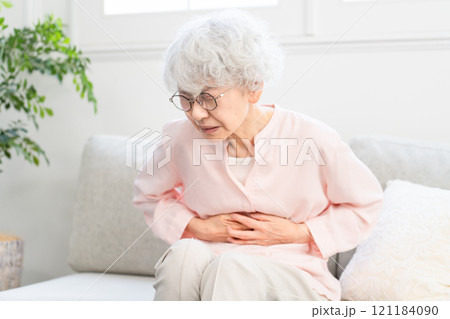 お腹を抱えるシニア女性 121184090