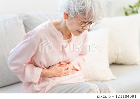 お腹を抱えるシニア女性 121184091