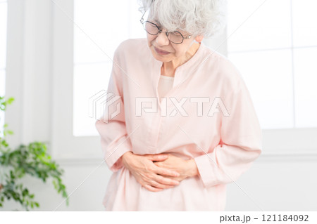 お腹を抱えるシニア女性 121184092