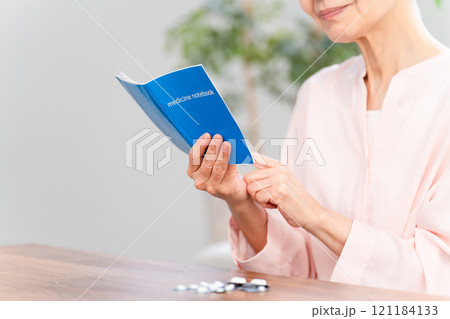 おくすり手帳を確認するシニア女性 おくすり手帳を確認するシニア女性 121184133