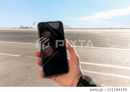Girl holds a smartphone with a black screen close-up. Phone on the background of the airport with an airplane 121184339