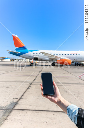 Girl holds a smartphone with a black screen close-up. Phone on the background of the airport with an airplane 121184342