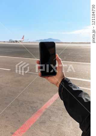 Girl holds a smartphone with a black screen close-up. Phone on the background of the airport with an airplane 121184730