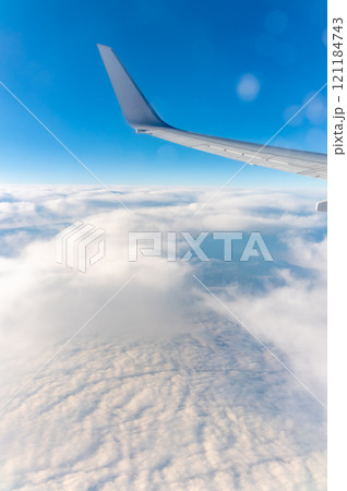 View from the airplane window at a beautiful cloudy sky and the airplane wing View from the airplane window at a beautiful cloudy sky and the airplane wing 121184743