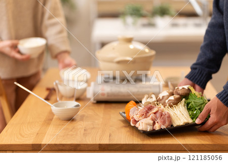 冬の夜のリビングで夕食の鍋料理の準備をするミドル夫婦 冬の夜のリビングで夕食の鍋料理の準備をするミドル夫婦 121185056