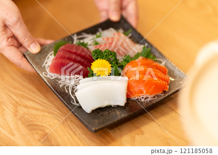 刺身の盛り合わせを食卓に運ぶミドル女性の手元 刺身の盛り合わせを食卓に運ぶミドル女性の手元 121185058