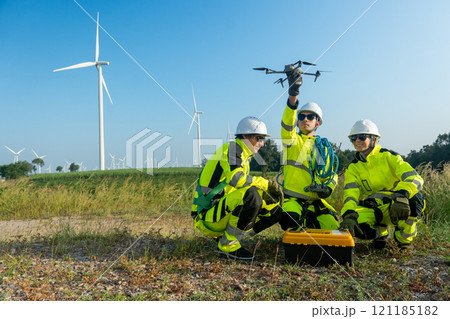 Wide shot of group of wind turbine or windmill workers or technician check for preparing to use drone in workplace field. 121185182