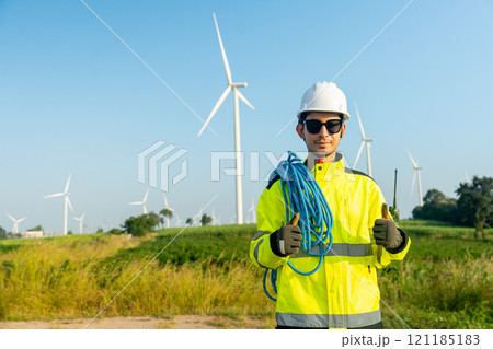Portrait of wind turbine worker or engineer man stand with arm-crossed and show thumbs up with row of wind turbine in the background. 121185183