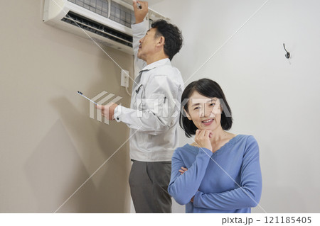 エアコンの故障の修理を業者に依頼する女性 エアコンの故障の修理を業者に依頼する女性 121185405