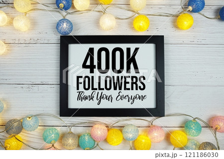 Thanks You 400000, 400K Followers text written on blackboard with LED cotton balls decoration on wooden background 121186030